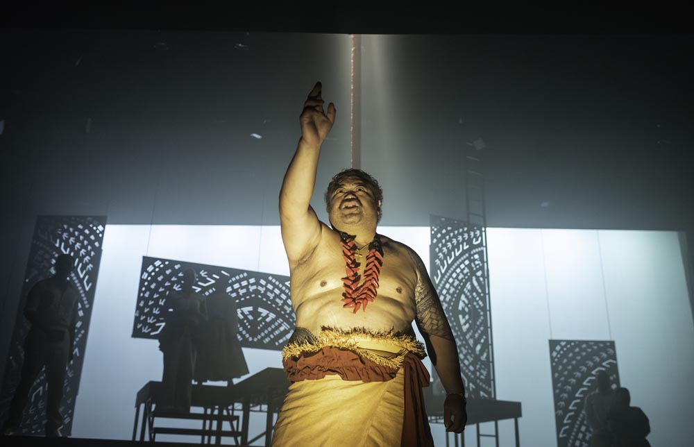 Auckland Theatre Company’s production of O le Pepelo, le Gaoi, ma le Pala’ai | The Liar, the Thief, and the Coward featured in the Auckland Arts Festival 2024 and included a relaxed performance. The image is of a man wearing a lavalava. He is bare-chested and his right hand is raised as he looks up.  Photo: Anna Benhak