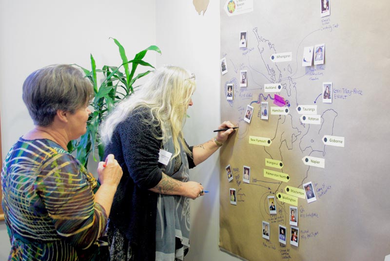 Conference delegates mark their place on a New Zealand map