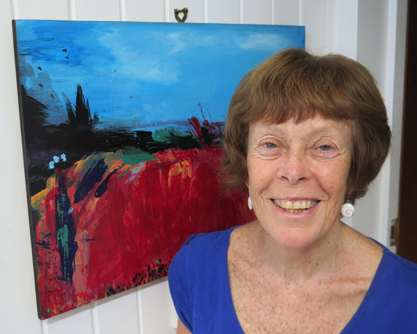 Portrait image of Iona McNaughton, standing alongside an artwork in Arts Access Aotearoa's office