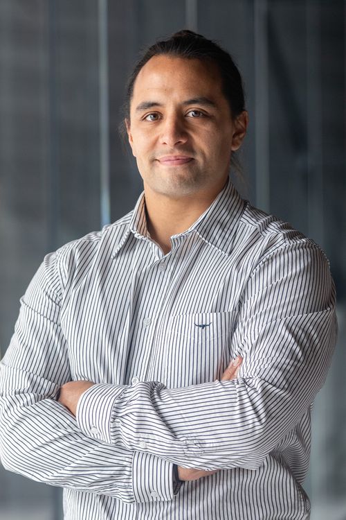 Aperahama Hurihanganui stands with arms folded looking at camera