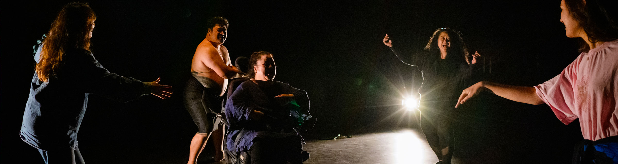 People dancing with Lusi Faiva in a wheelchair during a performance of Aiga