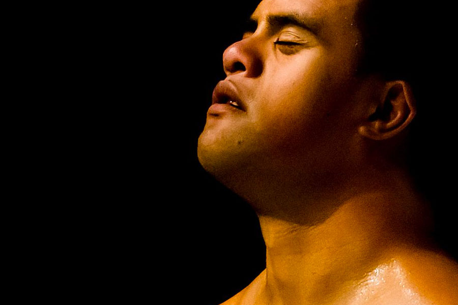 Close up of face with eyes closed on a black background with moody lighting.