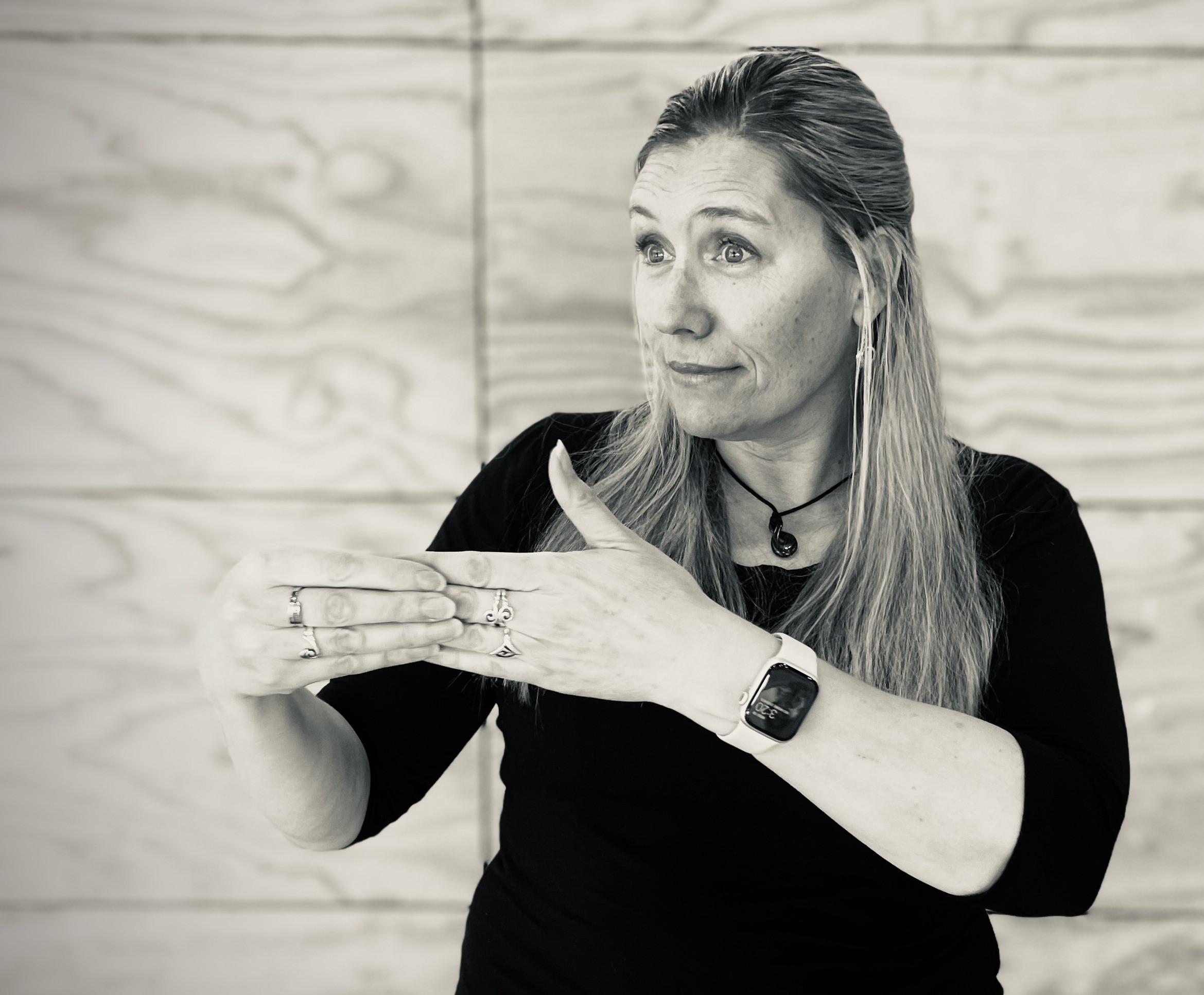 Rāhera stands signing to an audience out of shot. 