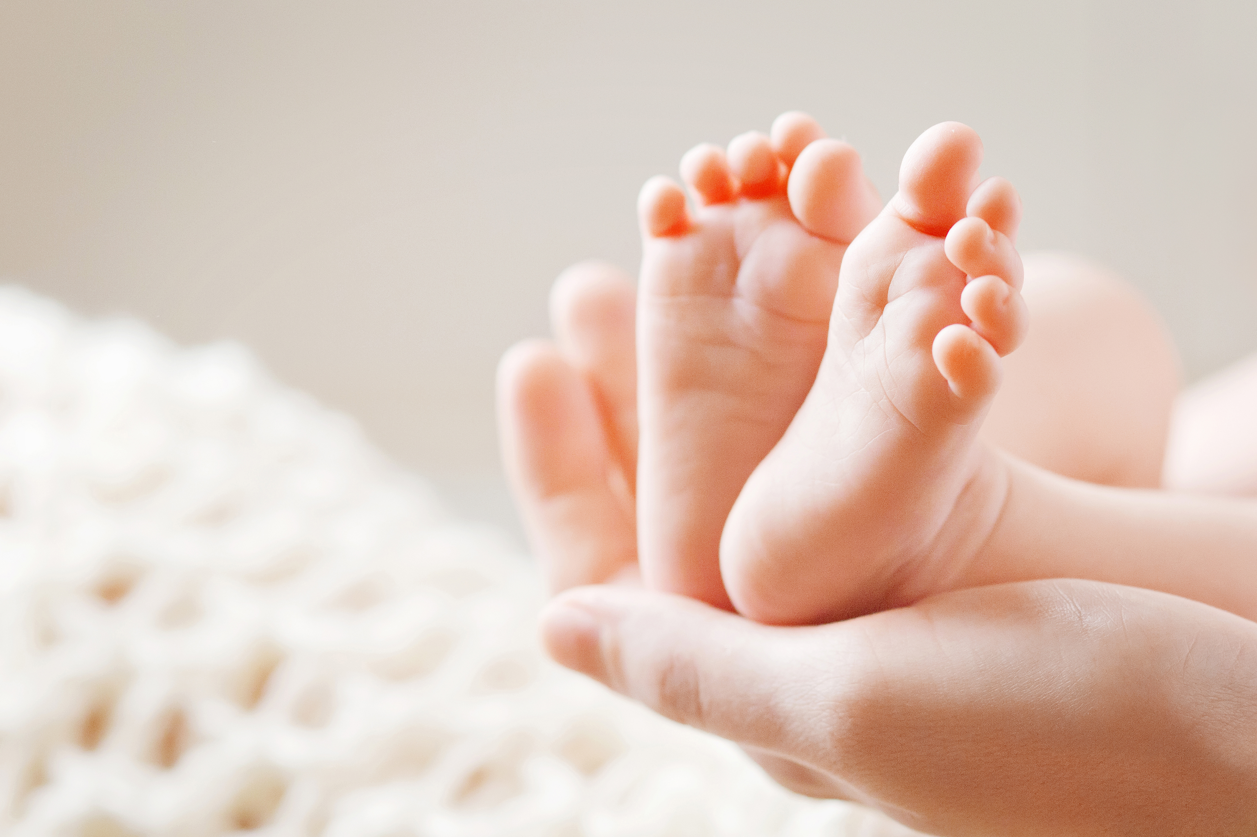 Image of woman holding baby feet.