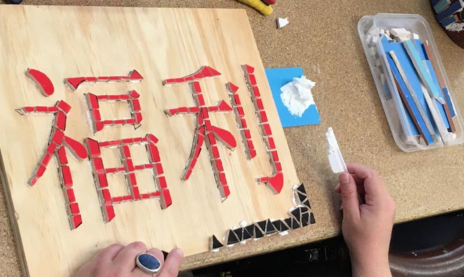 An artist creating a mosaic of Chinese characters